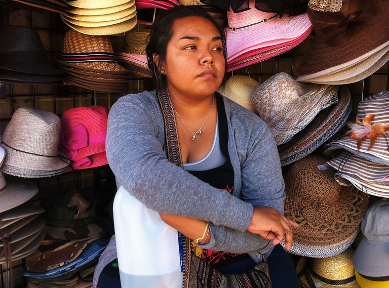 Woman sitting in front of hat display