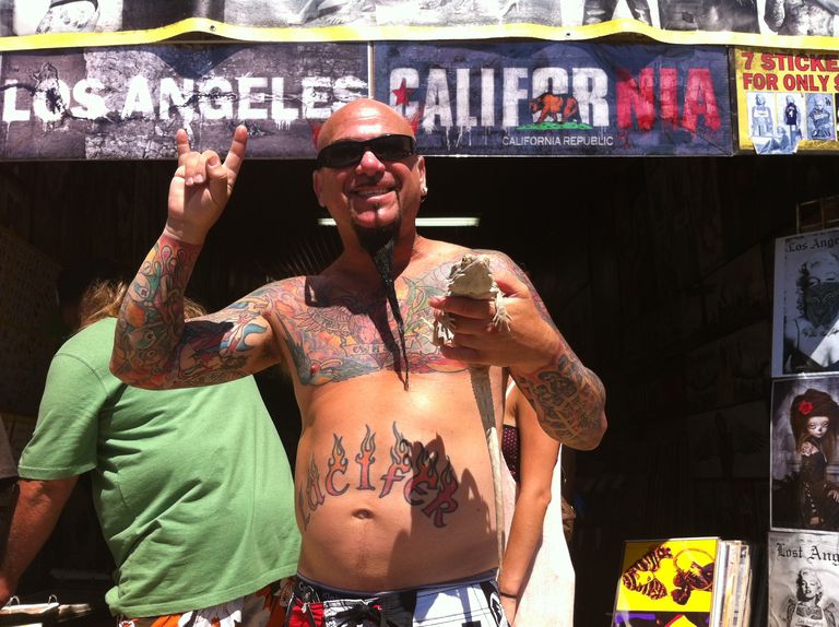 Tattooed man in front of LA banner holding lizard