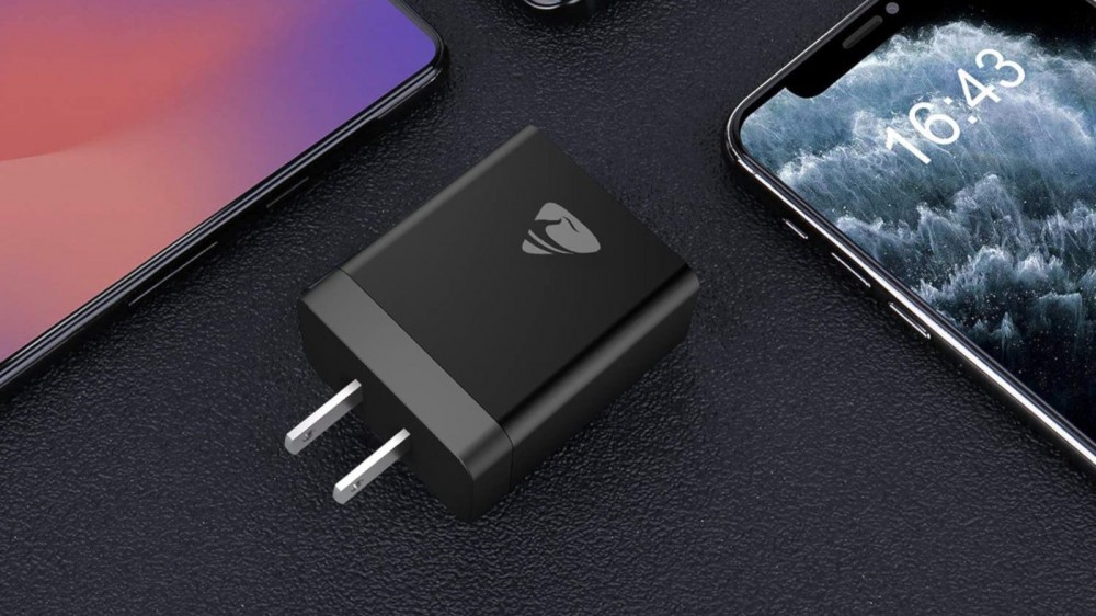 Black 4-port USB wall plug laid next to several smartphones 