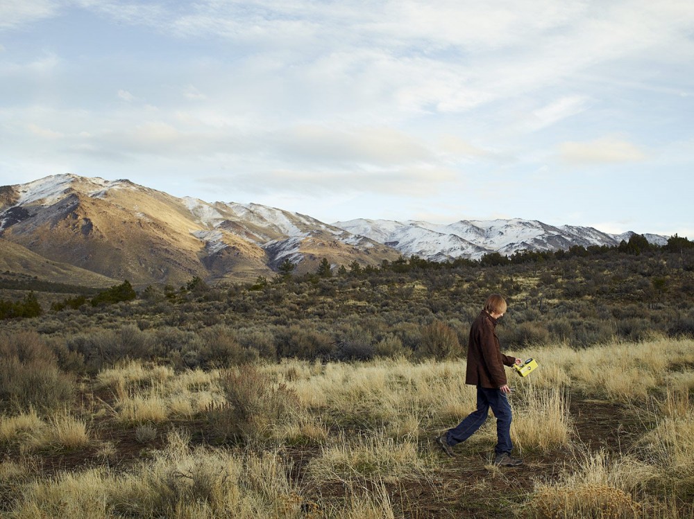 Taylor Wilson walking in front of a snowy Nevada mountain range while hunting for radioactive material